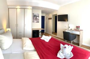 um quarto com um sofá branco e um cobertor vermelho em Aparthotel Kleine Perle em Cuxhaven
