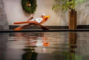 
a man sitting on a chair in a pool of water at Les Suites – Maison Bouvier in Tignes
