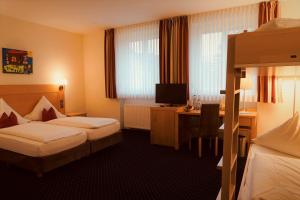 ein Hotelzimmer mit 2 Betten und einem Schreibtisch in der Unterkunft Klosterbräuhaus Ursberg in Ursberg