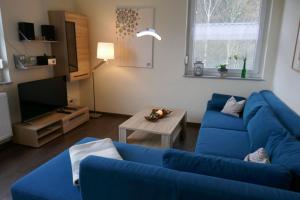 a living room with a blue couch and a tv at Landferien Eifel in Pittenbach