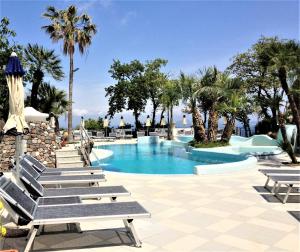 a swimming pool with lounge chairs and palm trees at Hotel Myage in Ischia
