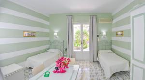Hotel Residence Mendolita في ليباري: غرفة بسريرين وطاولة بها ورد