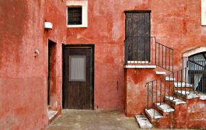 a red building with a door and a staircase at Masseria Spina Resort in Monopoli