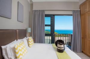 a bed sitting in front of a window with a view of the ocean at Brenton Haven Beachfront Resort in Brenton-on-Sea
