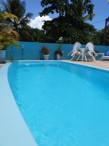 una gran piscina azul con sillas y una valla en Pousada Mikaela Arraial, en Arraial d'Ajuda