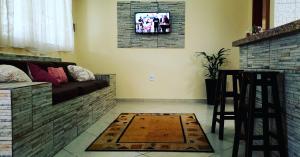 Villaggio Avansi في كاراغواتاتوبا: غرفة معيشة مع أريكة وتلفزيون على الحائط