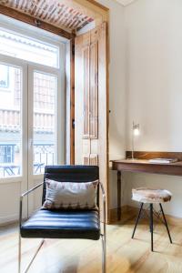 una sedia con cuscino in una stanza con pianoforte di Charming Flat with Balconies Central Chiado District 2 Bedrooms & AC 19th Century Building a Lisbona
