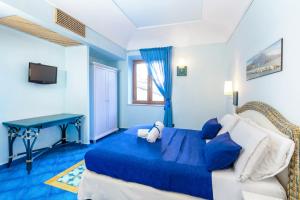 a blue bedroom with a bed and a table at Hotel Myage in Ischia