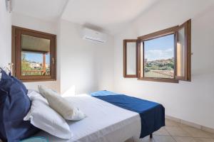 a bedroom with a bed and two windows at Appartamenti Tanaunella in Budoni