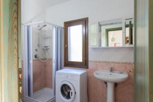ein Badezimmer mit einer Waschmaschine und einem Waschbecken in der Unterkunft Appartamenti Tanaunella in Budoni