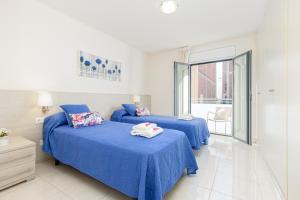 two beds in a room with blue sheets at Apart-rent Apartamento Francesc Macia 1º 2002 in Roses