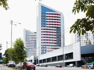 un edificio alto con coches estacionados frente a él en Modern new cozy apartment Kvartet Railway Station en Kiev