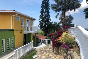 een geel en groen gebouw met een wit hek en bloemen bij Casa con piscina y zona de BBQ en la Mesa Cundinamarca in Anapoima