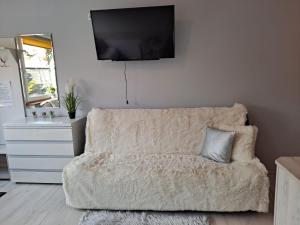 uma sala de estar com um sofá e uma televisão na parede em Pokoje Gościnne Biura Turystycznego KRIS em Kudowa-Zdrój