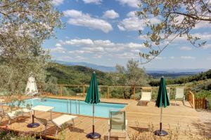 una piscina con sillas y sombrillas en una terraza de madera en Il Fienile en Figline Valdarno