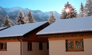 a house with snow covered roofs with mountains in the background at Chalet Presanella in Temù