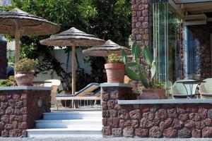 un patio con sillas, sombrillas y plantas en Thousand Stars Suites&Rooms en Kamari