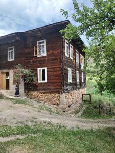 une maison en bois avec une personne debout devant elle dans l'établissement Farvana, à Didachara