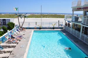 una piscina en un hotel con sillas y un edificio en Coliseum Ocean Resort, en Wildwood Crest