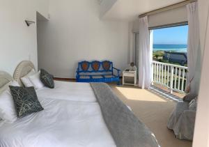a bedroom with a large white bed and a balcony at Southern Cross Beach House in Groot Brak Rivier