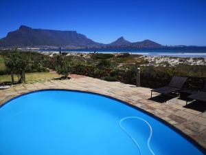 una piscina con vistas al océano y a las montañas en Cape Town Family Beachfront Apartment Leisure Bay en Ciudad del Cabo