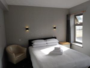 a bedroom with a white bed and a chair at Marine Hotel in Buckie