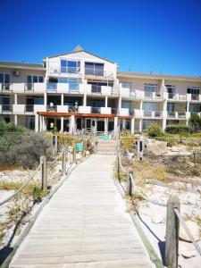 un paseo marítimo que conduce a un edificio en la playa en Cape Town Family Beachfront Apartment Leisure Bay en Ciudad del Cabo