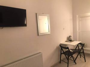 Zimmer mit einem Tisch und 2 Stühlen sowie einem TV an der Wand in der Unterkunft Y Panzió in Balatonlelle