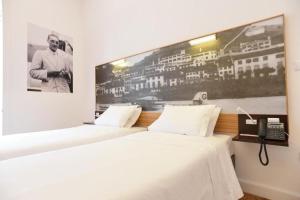 twee bedden in een kamer met een foto aan de muur bij Internacional Azores Boutique in Horta