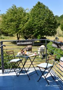- une table et deux chaises sur un balcon avec des animaux dans l'établissement Le Fenil Aux Ânes, à Walcourt
