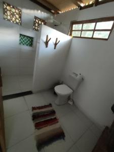 La salle de bains est pourvue de toilettes et de 2 croix sur le mur. dans l'établissement Espaço Pé de Mangaba - Natureza e Simplicidade, à Cumuruxatiba