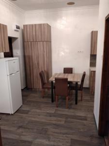 cocina con mesa, sillas y nevera en Bem Downtown Apartment, en Debrecen
