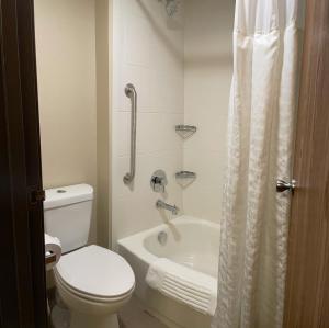 a bathroom with a toilet and a tub and a shower at Wingate by Wyndham West Mifflin in West Mifflin