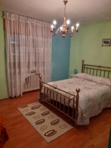 ein Schlafzimmer mit einem Bett mit einem Kronleuchter und einem Teppich in der Unterkunft Casa Gravere bis in Gravere