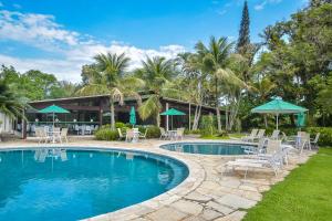 einen Pool mit Stühlen und Sonnenschirmen vor einem Resort in der Unterkunft Flat Privativo Reserva do Mar in Angra dos Reis