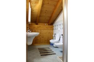 a bathroom with two toilets and two sinks at Chalet Presanella in Temù