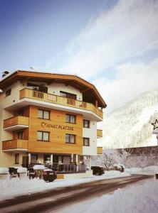 a building in the snow next to a mountain at Apart Platzer in Zell am Ziller