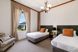 a bedroom with two beds and a couch and a window at Historic Stonehouse & Alley Cottage - Sleeps 14 with spa pool in Queenstown