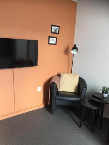 a living room with a chair and a flat screen tv at Studio met woonslaapkamer,keuken en badkamer Dreefje 5 in Westkapelle