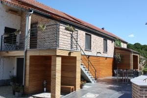 a house with a wooden facade and a patio at Le Fenil Aux Ânes in Walcourt
