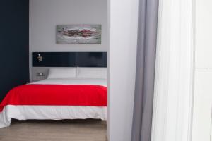 um quarto com uma cama com um cobertor vermelho em Hotel Santa Eulalia em Puertollano