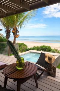 une terrasse en bois avec une table et une piscine dans l'établissement Arennas Mancora, à Máncora