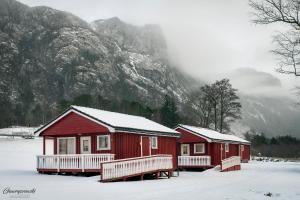 duas cabanas vermelhas com neve sobre elas em frente a uma montanha em Wathne Camping em Bjørheimsbygda