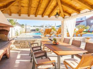 an outdoor patio with a wooden table and chairs at Maslina in Vrsi