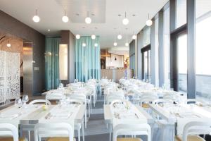 una sala da pranzo con tavoli e sedie bianchi di Ibis Styles Roma Eur a Roma