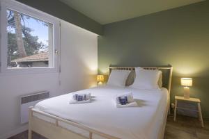 a bedroom with a large white bed with a window at Appartement Sémaphore - Welkeys in Soorts-Hossegor