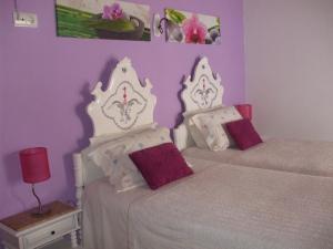 two beds in a bedroom with purple walls at Dinas Guesthouse in Lagos