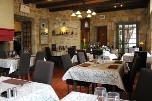 un ristorante con tavoli, sedie e orologio di Logis Hotels- Auberge de la Tour - Hôtel et restaurant a Sauzet