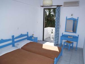 a bedroom with two beds and a mirror and a window at Nikos Apartments & Studios in Plakias