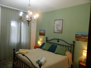 a bedroom with a bed with green walls and a chandelier at Casa di zio in Monticiano